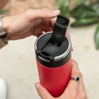 A male holding an Ever Vessel Super Maxi Red stainless steel water bottle with the flip top lid open.