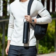 A male carrying his Ever Vessel Super Maxi Black stainless steel water bottle by the integrated handle at university.