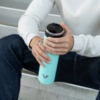 A male holding an Ever Vessel Super Maxi Mint green stainless steel water bottle with the flip top lid open.