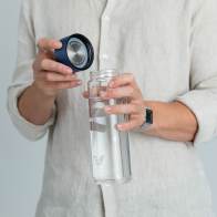 A male about to drink from his Ever Vessel Glass water bottle with blue lid removed at home.