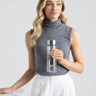 A female holding her Ever Vessel Glass water bottle with stainless lid above a stone table at work.