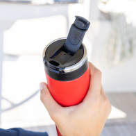 A male about to drink from his Ever Vessel Maxi Red stainless steel water bottle with leak-proof flip lid open on a yacht.