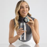 Female holding her optically clear borosilicate glass water bottle, with mint green lid off at the office.