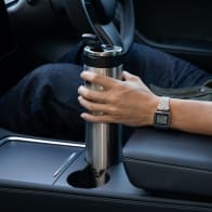 A male placing an Ever Vessel Super Maxi stainless steel water bottle into a car cup holder with the leak-proof flip top open.