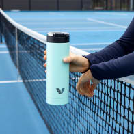 Female holding her Ever Vessel Maxi Mint Green stainless steel water bottle over the tennis court net.