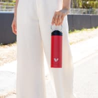Female carrying her Ever Vessel Maxi Red stainless steel water bottle by the integrated carry handle trackside.