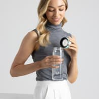 A female removing the lid from her Ever Vessel Glass water bottle with mint green lid at the office.