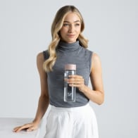 A female holding her Ever Vessel Glass water bottle with rose pink lid at work.