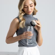 A female removing the lid from her Ever Vessel Glass water bottle with desert beige lid at the office.