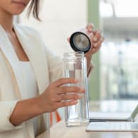 A female about to drink from her Ever Vessel Glass Multi double walled glass tea infuser bottle with the rose pink lid removed.