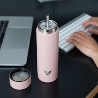 An Ever Vessel Multi Rose pink stainless steel tea infuser water bottle with the Straw Attachment accessory sitting on a desk.