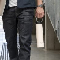 Male carrying his Super Maxi Luna White stainless steel water bottle by the integrated handle on the way to study.