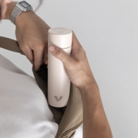 A male taking out his Ever Vessel Mini Luna White small water bottle from a small sling.