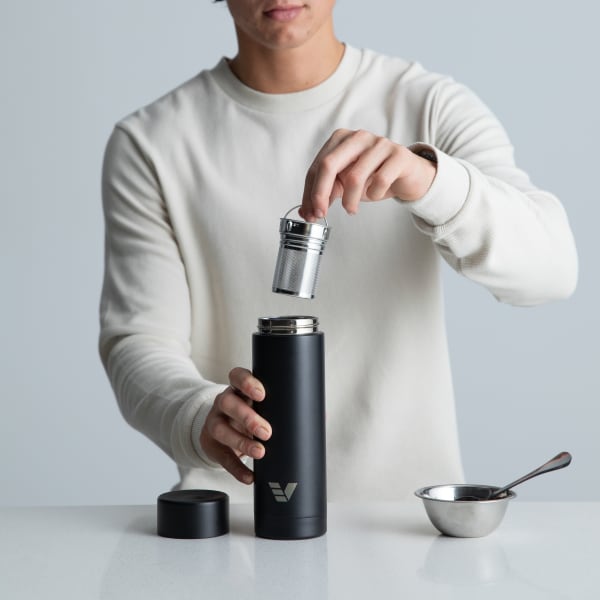 A male inserting the tea infuser into his Ever Vessel Multi Black stainless steel tea infuser water bottle at the kitchen bench.
