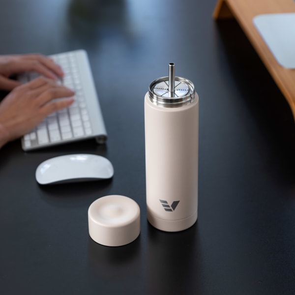 An Ever Vessel Multi Desert beige stainless steel tea infuser water bottle with the Straw Attachment accessory sitting  on a desk.