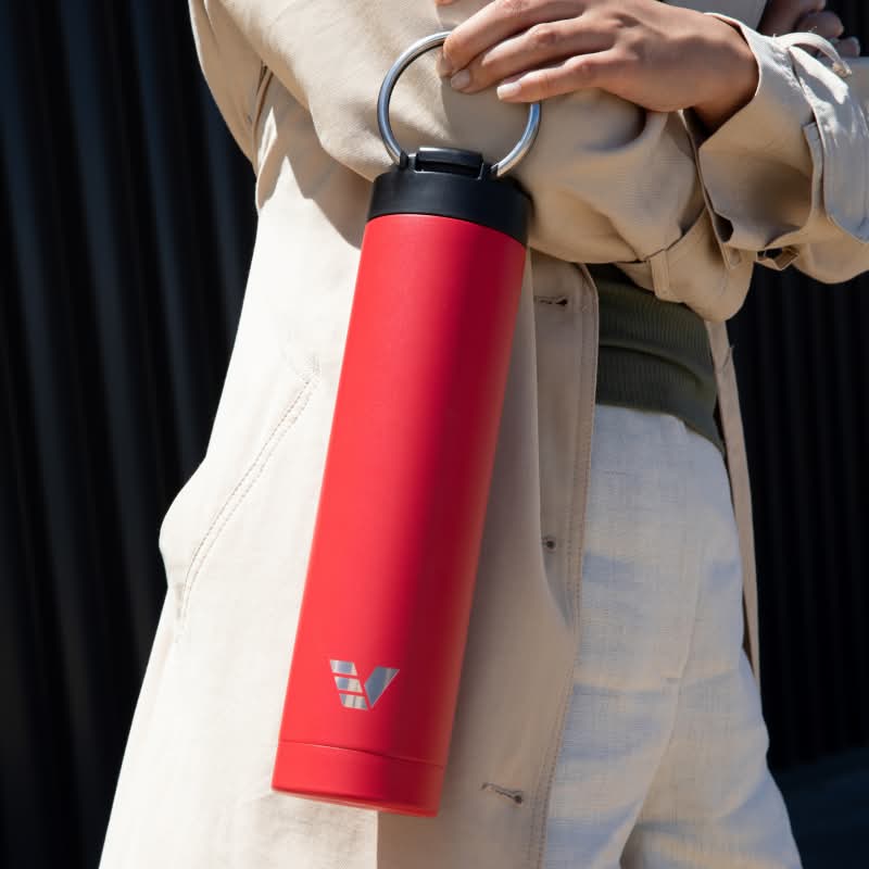 A female holding her Ever Vessel Super Maxi Red water bottle by the integrated handle.