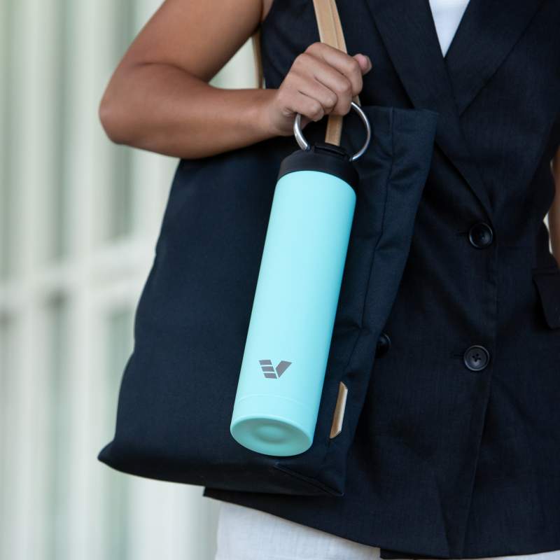 A female carrying her Ever Vessel Super Maxi Mint Green stainless steel water bottle by the integrated carry handle from work.