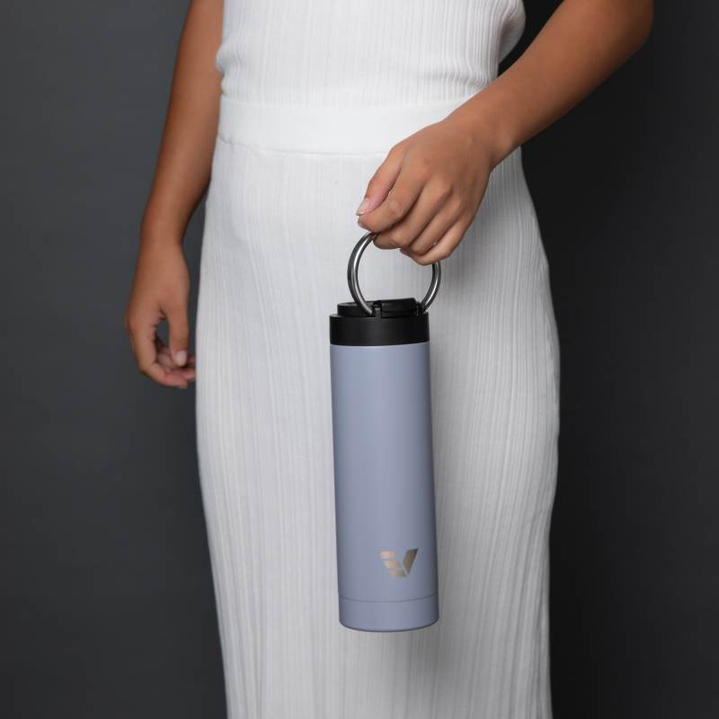 A female holding her Ever Vessel Maxi Lilac stainless steel water bottle by the integrated carry handle.