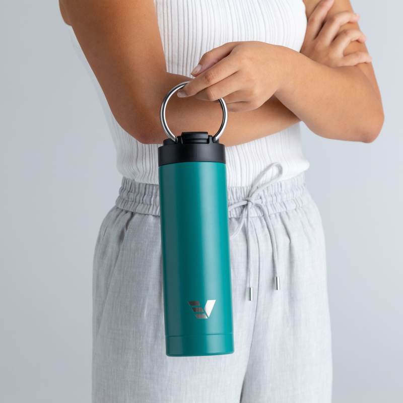 A female holding her Ever Vessel Maxi Teal green stainless steel water bottle by the integrated carry handle.