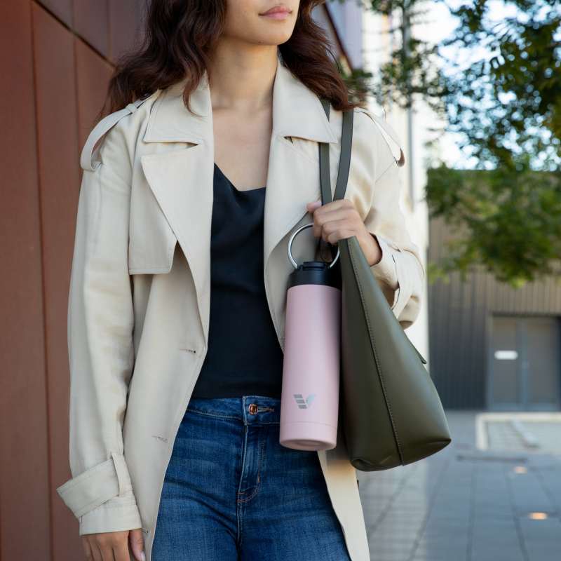 A female carrying her Ever Vessel Maxi Rose Pink stainless steel water bottle by the integrated carry handle on the way to work.