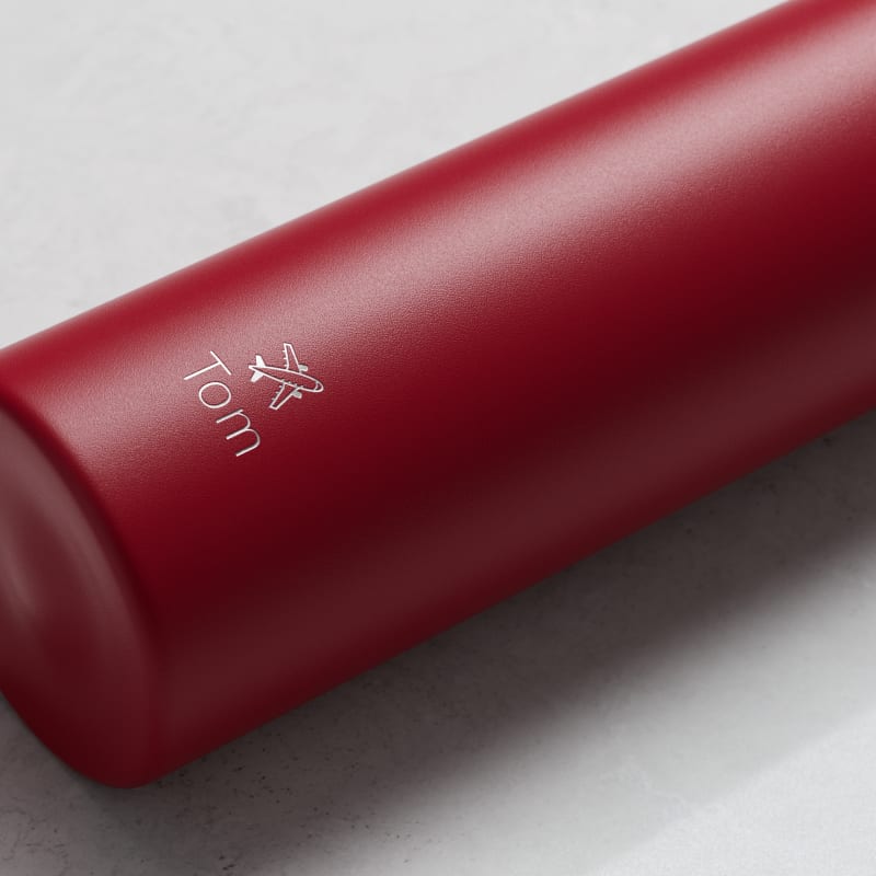 An Ever Vessel Mini Red  Personalized small water bottle with a name Tom and plane emoji engraved on the side.