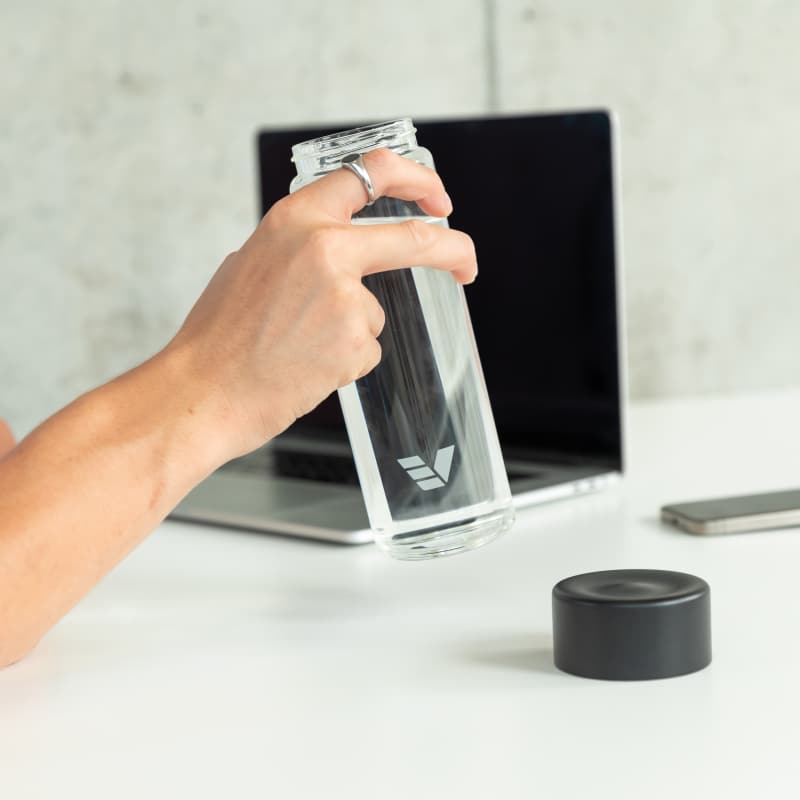 A male about to drink from his Ever Vessel Glass water bottle with a black lid at the office.