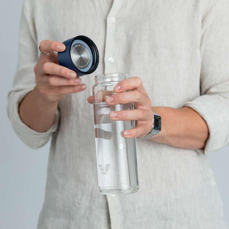 A male about to drink from his Ever Vessel Glass water bottle with blue lid removed at home.