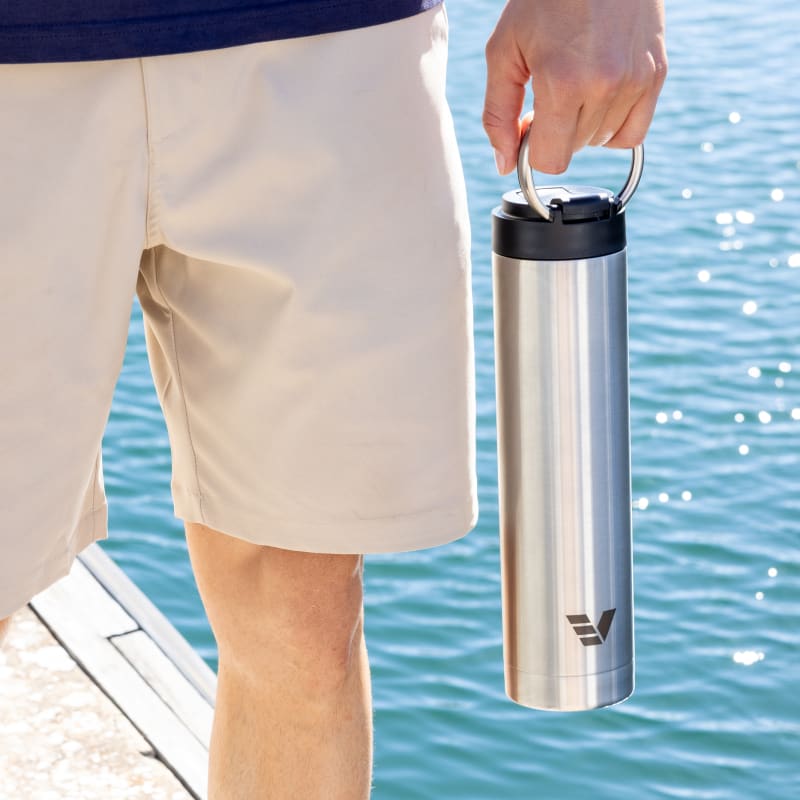 A male holding his Ever Vessel Super Maxi stainless steel water bottle by the integrated carry handle at the marina dock.