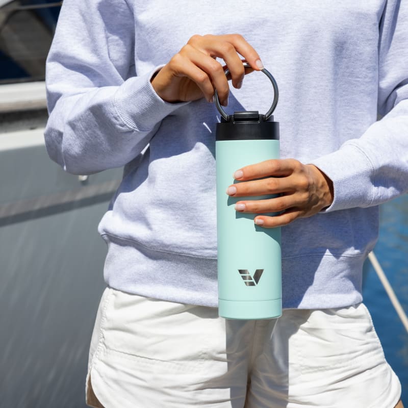 A female holding her Ever Vessel Maxi Mint Green stainless steel water bottle by the integrated carry handle at the marina dock.