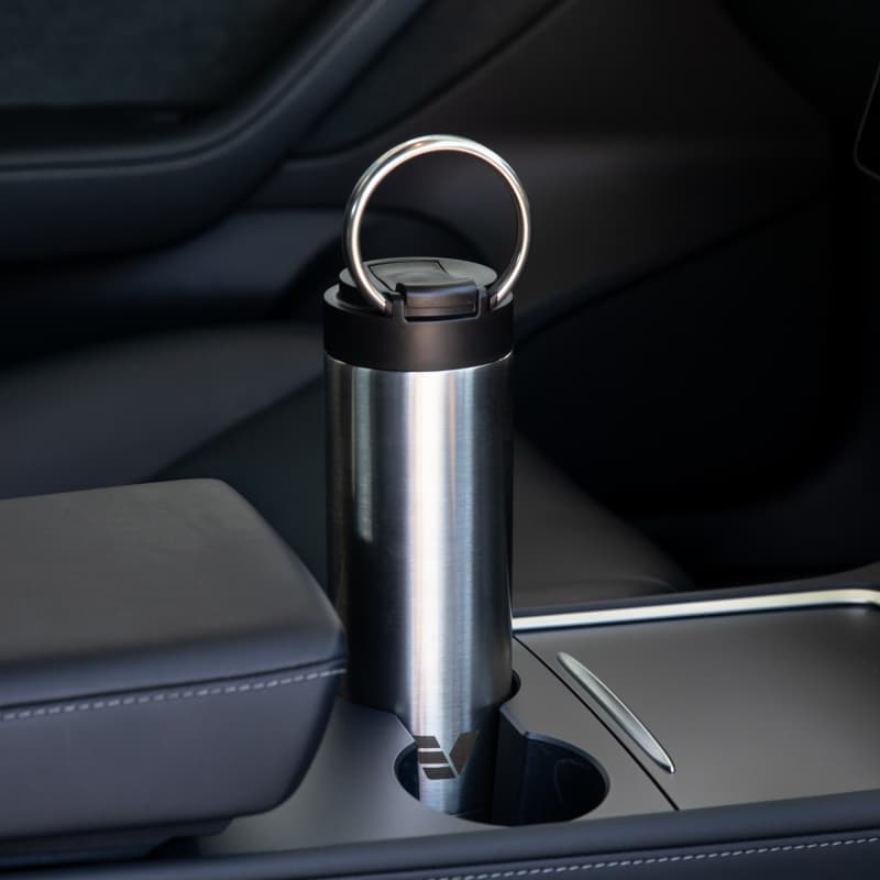 An Ever Vessel Maxi stainless steel water bottle sitting in car cup holder with integrated carry handle deployed.