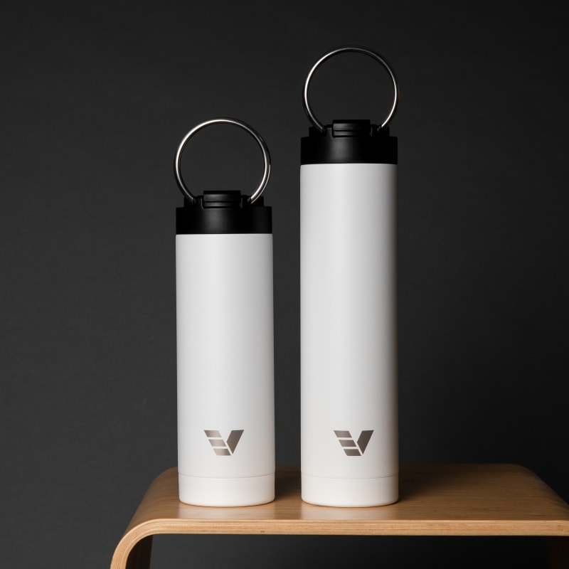 An Ever Vessel Super Maxi and Maxi White on a wooden stool with the integrated handles deployed.