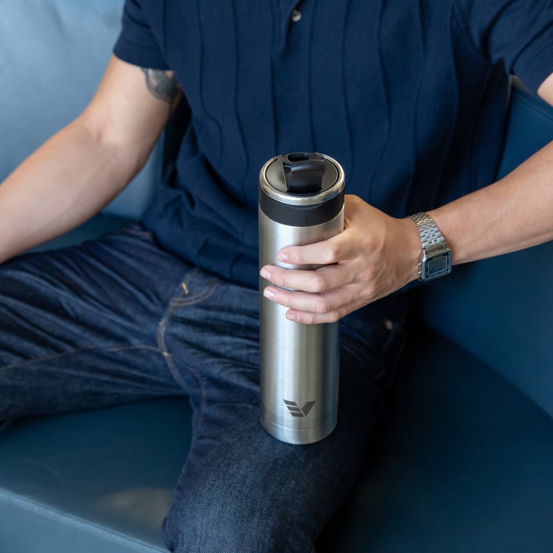 A male about to drink from his Ever Vessel Super Maxi stainless steel water bottle at an airport lounge.