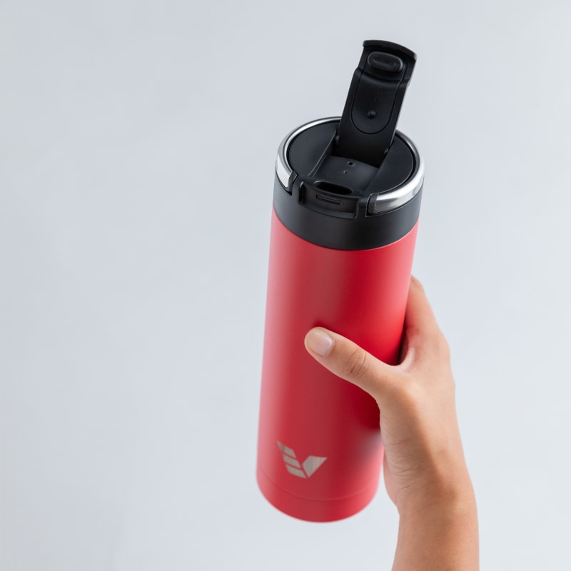 A female holding an Ever Vessel Maxi Red stainless steel water bottle with the leak-proof flip top open.