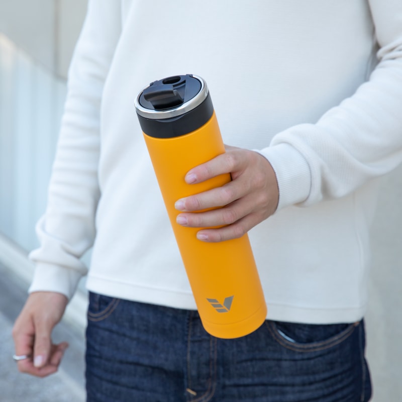 Male about to drink from his Super Maxi Yellow stainless steel water bottle with the leak-proof flip top open.
