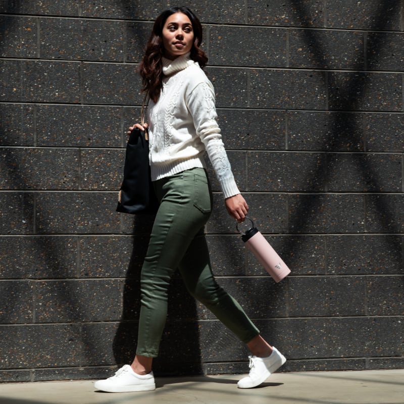 Female carrying her Ever Vessel Maxi Rose pink stainless steel water bottle by the integrated carry handle on the way to work.