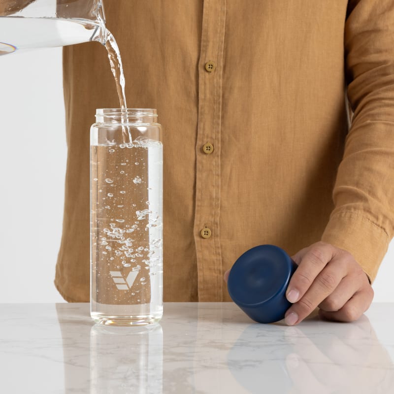 A male filling his Ever Vessel Glass water bottle with blue lid at home.