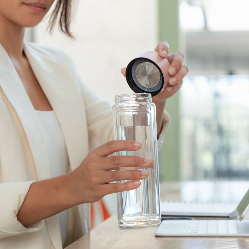 A female about to drink from her Ever Vessel Glass Multi double walled glass tea infuser bottle with the rose pink lid removed.