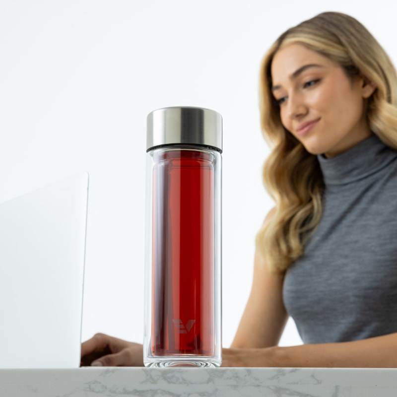 A female at her desk with her Ever Vessel Glass Multi tea infuser water bottle with tea inside by her side.