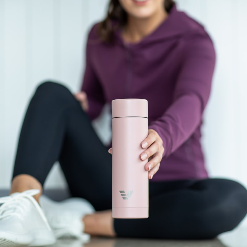 Female at the gym lifting an Ever Vessel Multi Rose pink tea infuser water bottle.