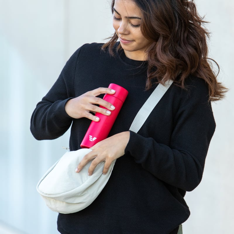 A female putting her Ever Vessel Mini Red small water bottle into a small sling.