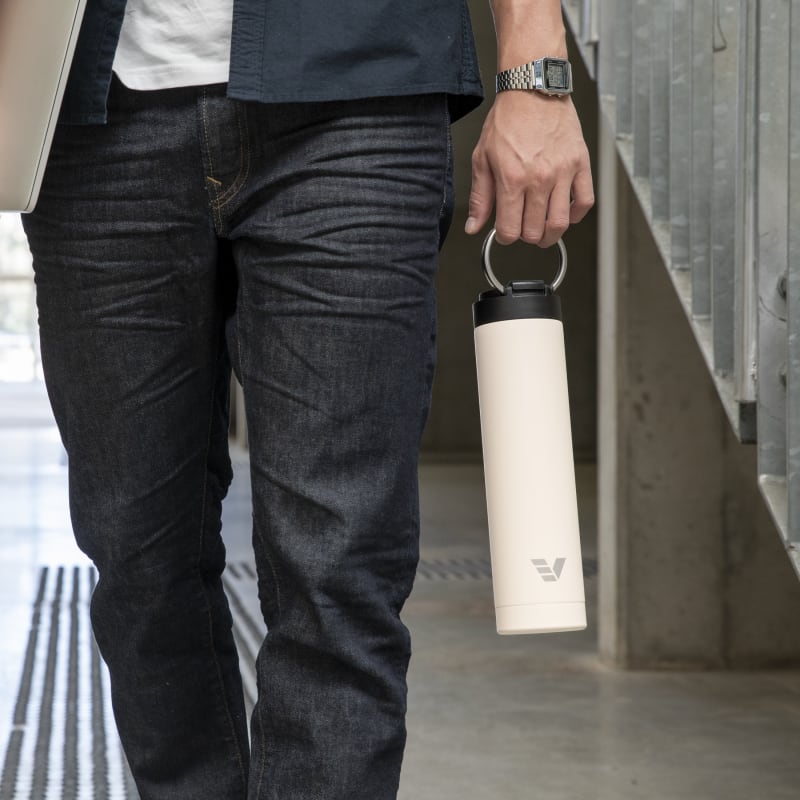 Male carrying his Super Maxi Luna White stainless steel water bottle by the integrated handle on the way to study.