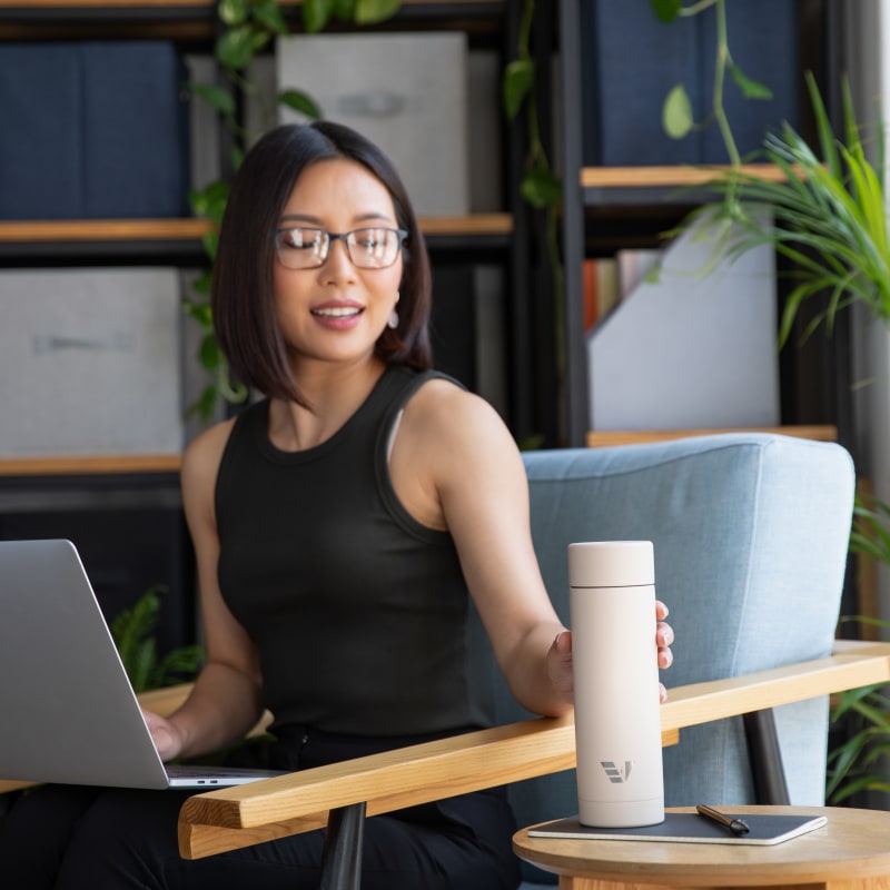 A female reaching for her Ever Vessel Multi Desert beige stainless steel tea infuser water bottle at the work cafe.