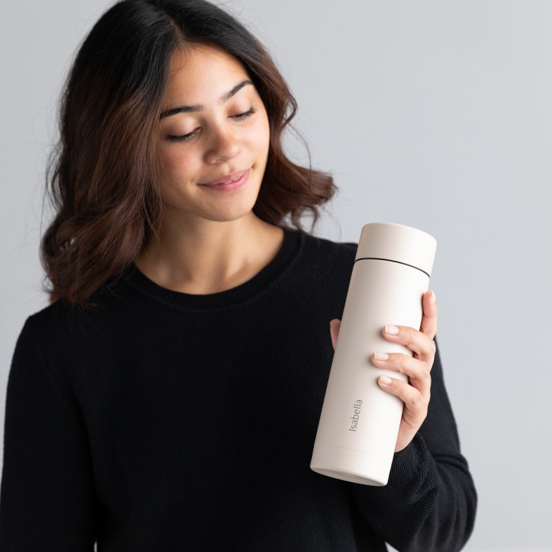 A female holding her Personalized Ever Vessel Multi Desert beige stainless steel tea infuser water bottle with the name Insabella laser engraved  on the side.