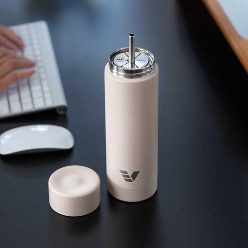 An Ever Vessel Multi Desert beige stainless steel tea infuser water bottle with the Straw Attachment accessory sitting on a desk.