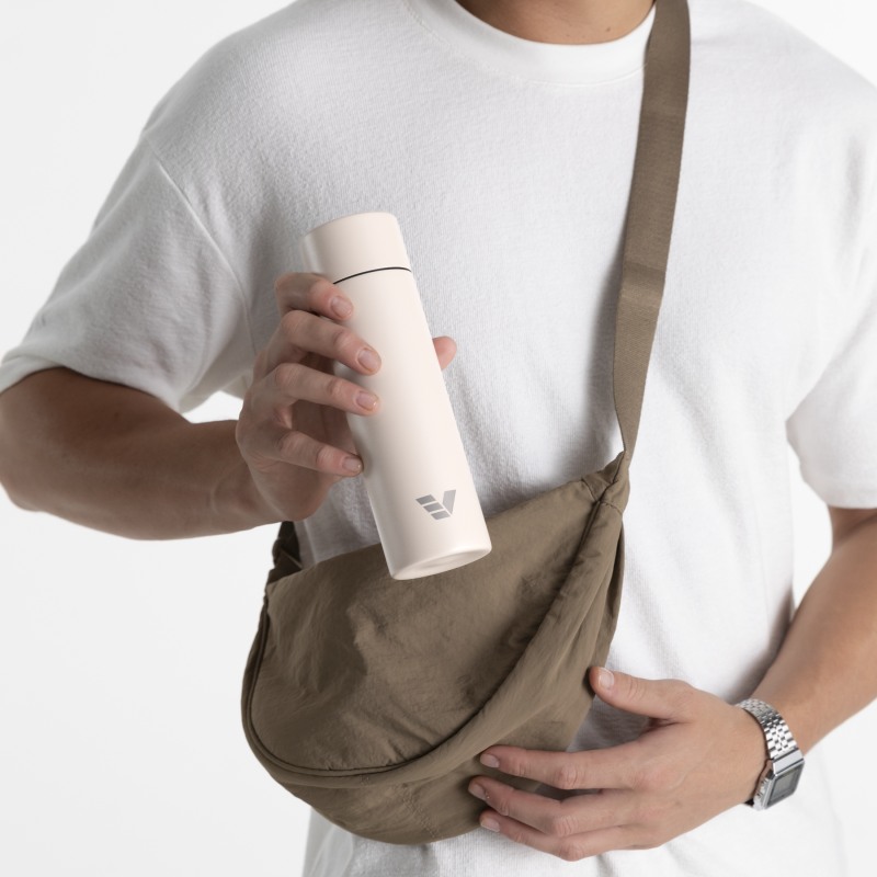 A male putting his Ever Vessel Mini Luna White small water bottle into a small sling.