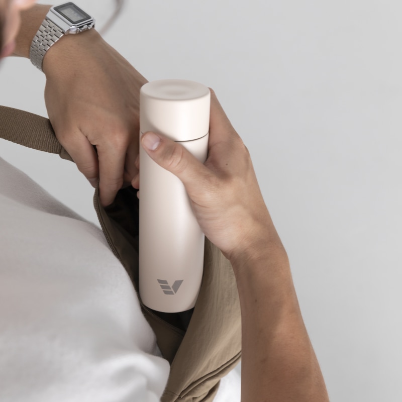 A male taking out his Ever Vessel Mini Luna White small water bottle from a small sling.
