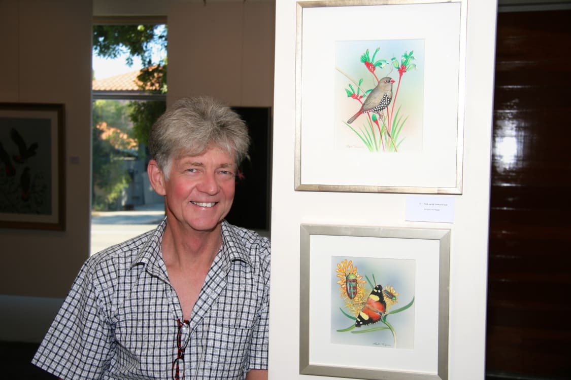 Picture of artist Martin Thompson at an Exhibition standing next to his art
